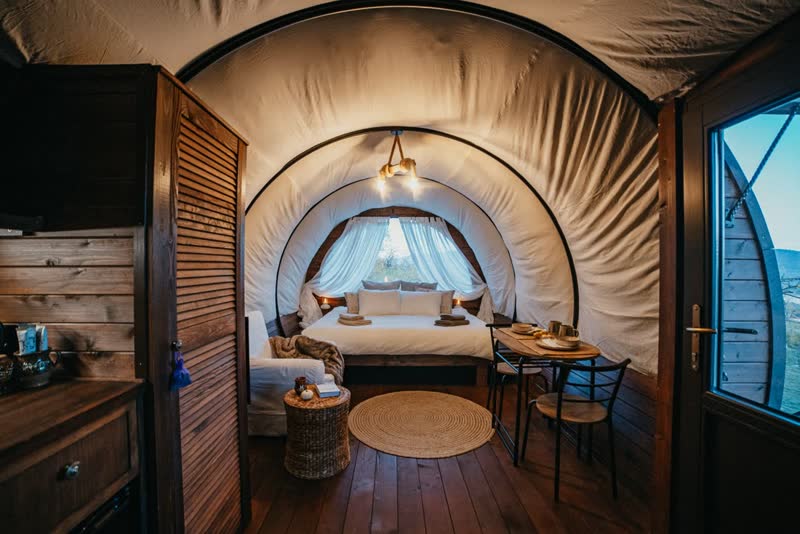 Innenraum des Glamping-Schäferwagens mit Holzverkleidung, Bett und Fenstern